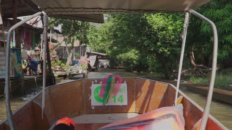 Moving-Forward-shot,-Inside-the-wooden-boat-in-the-Damnoen-Sudoku-River,-Shops-and-Houses-along-the-river-in-the-background