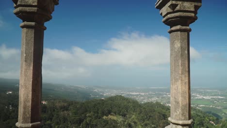 Einspielung,-Vorwärtsbewegung-Zwischen-Den-Beiden-Säulen-Des-Pena-Nationalpalastes,-Malerischer-Blick-Auf-Die-Waldlandschaft-Und-Die-Stadt-Im-Hintergrund