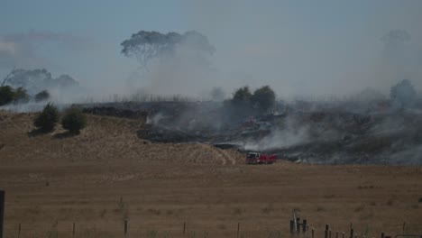 Single-fire-truck-hosing-edge-of-large-grass-fire