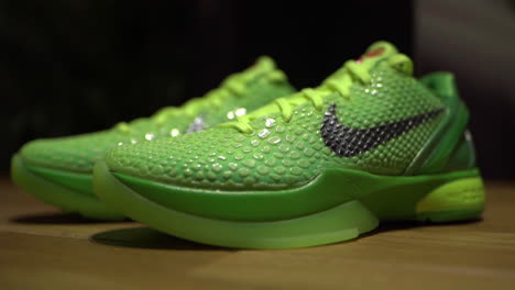 Zapatos-Nike-Kobe-6-Protro-Grinch-2020-Verdes-Filmados-Sobre-Una-Mesa-Marrón-Con-Fondo-Oscuro