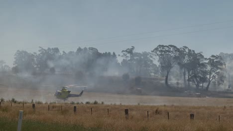 Helicóptero-Recogiendo-Agua-De-La-Presa-Con-Bomberos-Y-Camiones-De-Bomberos-En-Segundo-Plano.