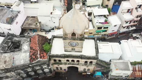 Antena-De-La-Torre-Raya-Naka-Con-La-Cámara-Panorámica-Hacia-Abajo-Y-Mostrando-Toda-La-Torre-Del-Reloj-Rodeada-De-Cadenas-De-Calles