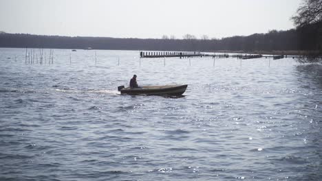 A-man-rides-in-a-motorboat-across-the-idyllic,-deep-blue-water,-which-reflects-the-incident-sunlight-dreamlike