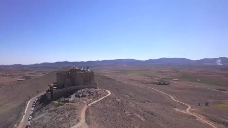 Drone-Shot,-aerial-view-with-pan-left-movement-and-point-of-view-around-the-castle-of-Calderigo,-Consuegra,-Spain