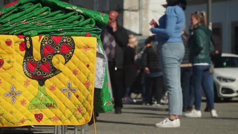 Trucking-Focus-shot,-Yellow-rug-with-Roster-Emblem-design-and-other-green-rugs,-Tourist-blurred-in-the-background