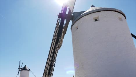 Toma-En-Cámara-Lenta-Del-Rotor-De-La-Pala-De-Un-Molino-De-Viento-Moviéndose-Frente-Al-Sol,-La-Ubicación-Es-Consuegra-En-España,-El-Lugar-De-Don-Quijote-Y-El-Robo-De-Dinero,-Casa-De-Papel