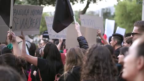 Una-Multitud-De-Hombres-Y-Mujeres-Marchan,-Cantan-Y-Protestan-Mientras-Sostienen-Carteles-Y-Banderas-Negras-Durante-El-Día-Internacional-De-La-Mujer.