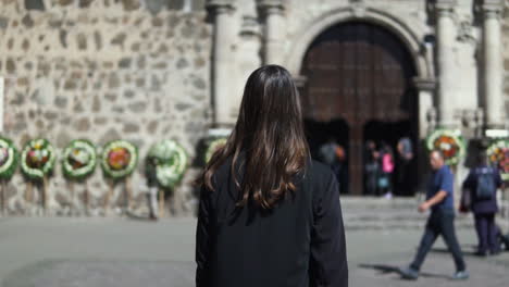 Brunette-girl-walking-towards-to-Santiago-Apostol-church-in-Tequila-town,-Jalisco,-Mexico---Slow-motion