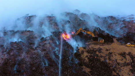 Luftaufnahme,-Verfolgung,-Drohnenaufnahme-Eines-Baggers,-Der-Einen-Waldbrand-Bekämpft,-Umgeben-Von-Rauch-Und-Flammen,-Düsterer-Abend,-In-Los-Angeles,-Kalifornien,-USA