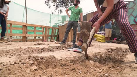 Close-Arc-Shot-Of-Girl,-Farmer-Tilling-Soil-Using-Pickaxe