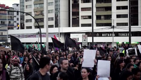 Una-Multitud-De-Mujeres-Y-Hombres-Vestidos-De-Negro-Sostienen-Carteles,-Banderas-Negras-Y-Una-Bandera-Lgtb-Durante-Una-Marcha-Y-Protesta-En-El-Día-Internacional-De-La-Mujer.