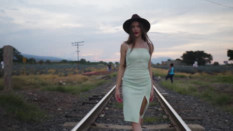 Attractive-Woman-Flirting-seductively-calling-for-lover-while-walking-on-train-track---Follow-slow-motion-wide-shot