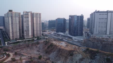 Aerial-view-revealing-Dallas-Center-Road-with-Qualcomm-Hyderabad-Campus-in-the-background,-new-development-in-contrast-with-the-destruction-of-the-Biodiversity-Park-due-to-road-construction