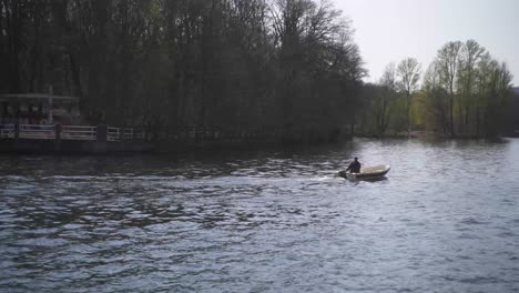 A-man-rides-in-a-motorboat-across-the-idyllic,-deep-blue-water,-which-reflects-the-incident-sunlight-dreamlike