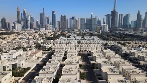 Sobrevuelo-Aéreo-Suburbio-Zona-Residencial-De-Dubai-Y-Horizonte-En-El-Fondo-Durante-El-Día-Soleado-Con-Cielo-Azul---Tiro-De-Camión-Inclinado-Hacia-Arriba