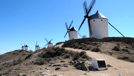 Paisaje-De-Molinos-De-Viento-En-España,-Sobre-Una-Exuberante-Colina-Sobre-Fondo-De-Cielo-Azul-En-Un-Día-De-Primavera