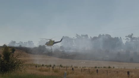 Helicóptero-Despegando-Después-De-Recoger-Agua-De-La-Presa,-Palas-Del-Rotor-Rociando-Agua-De-La-Presa