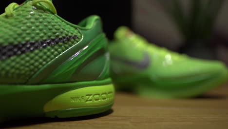 Grüne-Nike-Kobe-6-Protro-Grinch-2020-Schuhe,-Gefilmt-Auf-Einem-Braunen-Tisch-Mit-Dunklem-Hintergrund