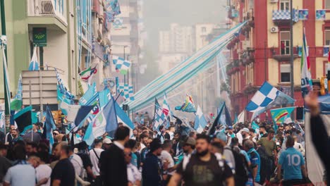 Plano-General-Que-Muestra-A-Una-Multitud-De-Aficionados-Italianos-En-La-Carretera-Celebrando-La-Victoria-Del-SSC-Napoli-En-La-Serie-A,-Ondeando-Banderas-En-La-Carretera-De-La-Ciudad-De-Nápoles,-Italia.