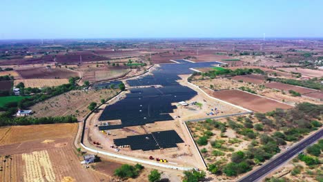 aerial-drone-wide-view-showing-the-entire-solar-farm-producing-green-energy,-wide-view-of-the-road