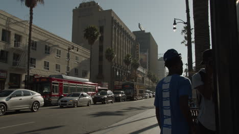 Cinematic-Golden-Hour-shot-of-people-hanging-out-on-the-corner-of-Hollywood-Blvd-with-Darth-Vader-performer-walking-in-the-background