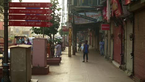 El-Famoso-Tablero-Con-El-Nombre-De-Paranthe-Wali-Gali-En-La-Calle-De-Chandni-Chowk,-Jornaleros-Trabajando-Temprano-En-La-Mañana