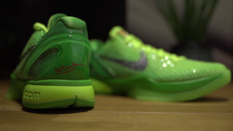 Grüne-Nike-Kobe-6-Protro-Grinch-2020-Schuhe-Gefilmt-Statisch-Auf-Einem-Braunen-Tisch-Mit-Dunklem-Hintergrund