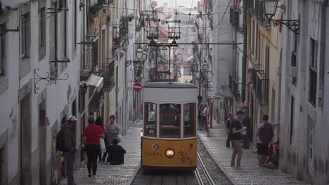 Tiro-De-Establecimiento,-Tranvía-Amarillo-Antiguo-En-El-Sendero-En-Lisboa,-Portugal,-Gente-Al-Costado-De-Las-Calles-En-El-Fondo