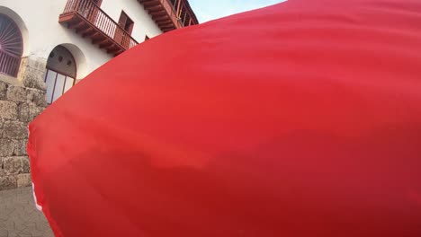 A-big-and-colorful-umbrella-is-seen-while-tourists-are-walking-down-the-street-of-the-old-town-of-Cartagena-de-Indias,-Colombia