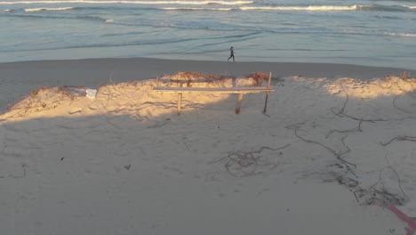 Light-sandy-calm-beach-of-Santinho-in-Florianópolis-with-a-lady-walking-on-the-shores-at-golden-hour