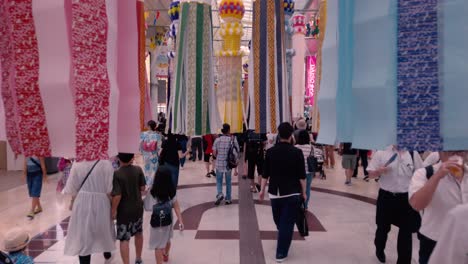 People-in-arcade-walking-through-decorative-paper-streamers-during-Tanabata-festival