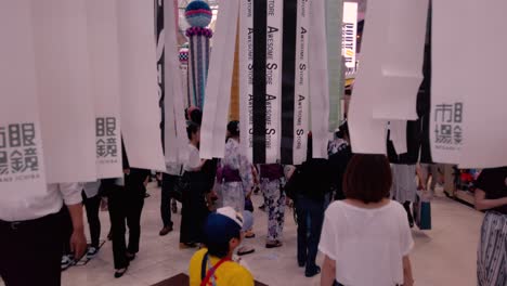 Gente-En-Arcade-Caminando-Entre-Serpentinas-De-Papel-Decorativas-Durante-El-Festival-De-Tanabata