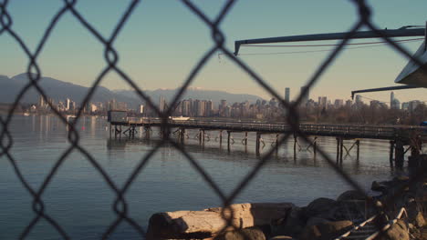 A-RIGHT-TO-LEFT-DOLLY-SHOT-Peeking-Through-a-Chain-Link-Fence-to-see-a-Dock-and-City-in-the-Distance