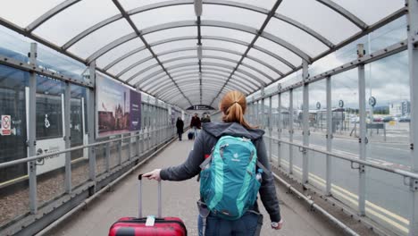 A-red-haired-woman-leaves-an-airport-with-her-luggage