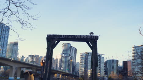 A-Left-to-Right-DOLLY-SHOT-of-a-Sign-Sitting-Against-a-City-Backdrop-that-Reads-"SHOULD-I-BE-WORRIED