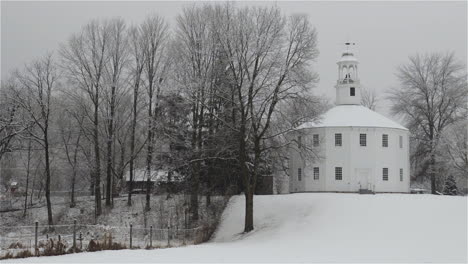 Toma-Panorámica-En-Cámara-Lenta-De-Nieve-Húmeda-Cayendo-A-Principios-De-Primavera-En-La-Antigua-Iglesia-Redonda-En-Richmond,-Vermont.