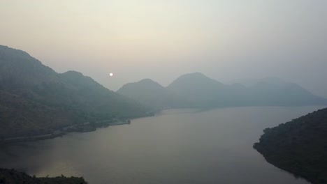 Beautiful-Sunrise-Over-The-Badi-Lake-And-Coastal-Mountains-With-A-Man-Standing-On-The-Edge-Of-Cliff