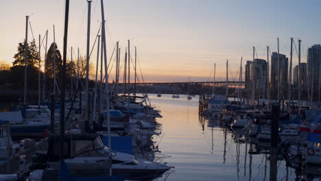 Una-Toma-De-Derecha-A-Izquierda-De-Un-Puerto-De-Vancouver-En-Stamps-Landing,-La-Puesta-De-Sol-Y-La-Ciudad-Al-Fondo