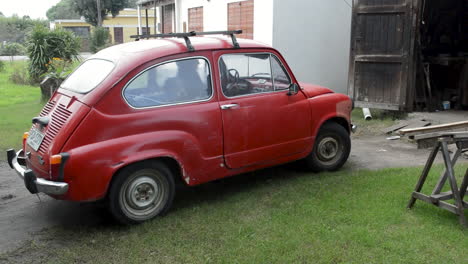 Old-man-driving-a-classic-red-car-from-his-home-garage