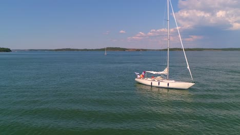 Aerial,-orbit,-drone-shot,-panning-around-a-sailboat-at-at-the-sea,-near-a-harbor,-on-Hogsara-Island,-in-the-finnish-archipelago,-on-a-sunny,-summer-day,-in-Varsinais-suomi,-Finland