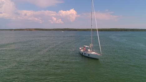 Sailboat-in-the-finnish-archipelago,-Aerial,-orbit,-drone-shot,-panning-around-a-boat-at-the-baltic-sea,-near-a-harbor,-on-Hogsara-Island,-on-a-sunny,-summer-day,-in-Varsinais-suomi,-Finland