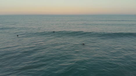 Surfers-floating-on-the-mild-calm-waves-of-Santinho-Beach-at-evening-golden-magic-hour