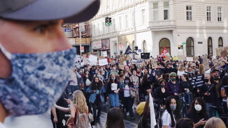 Una-Foto-De-Un-Hombre-Que-Llevaba-Una-Máscara-Para-Protegerse-Y-Observaba-A-Una-Multitud-Caminando-Y-Protestando-Contra-El-Racismo