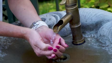 Woman-drinking-water-from-old-tap