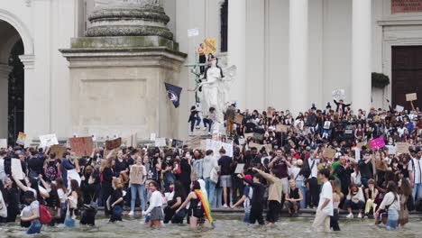 Eine-Aufnahme-Einer-Menschenmenge,-Die-Gegen-Rassismus-Protestiert,-Während-Sie-In-Einem-Brunnen-Vor-Einem-Gebäude-In-Wien-Steht