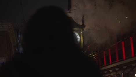 OVER-THE-SHOULDER-SHOT-of-Photographer-Taking-Pictures-of-Gastown-Clock-in-Snowy-Nighttime-Scene