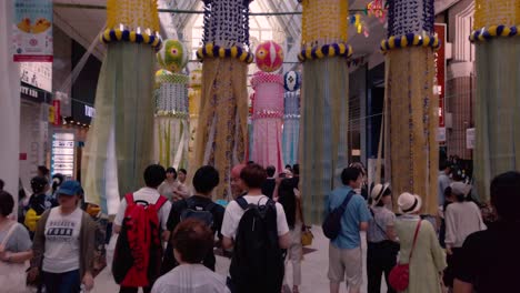 Gente-En-Arcade-Caminando-Entre-Serpentinas-De-Papel-Decorativas-Durante-El-Festival-De-Tanabata