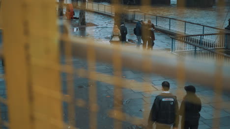 Slider-shot-of-people-walking-along-promenade-next-to-the-River-Thames-during-evening