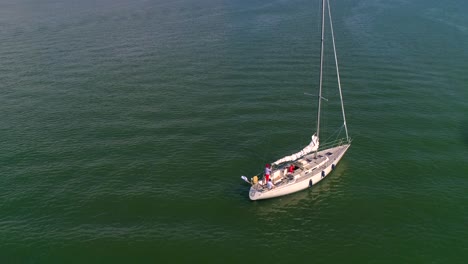 Aerial,-rising,-drone-shot,-of-a-sailboat-at-at-the-sea,-near-a-harbor,-on-Hogsara-Island,-in-the-finnish-archipelago,-on-a-sunny,-summer-day,-in-Varsinais-suomi,-Finland