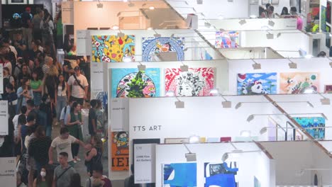 Bird's-eye-view-of-visitors-attending-an-art-fair-show-where-art-exhibitors-sell-paintings-and-sculptures-to-visitors,-art-enthusiasts,-and-collectors